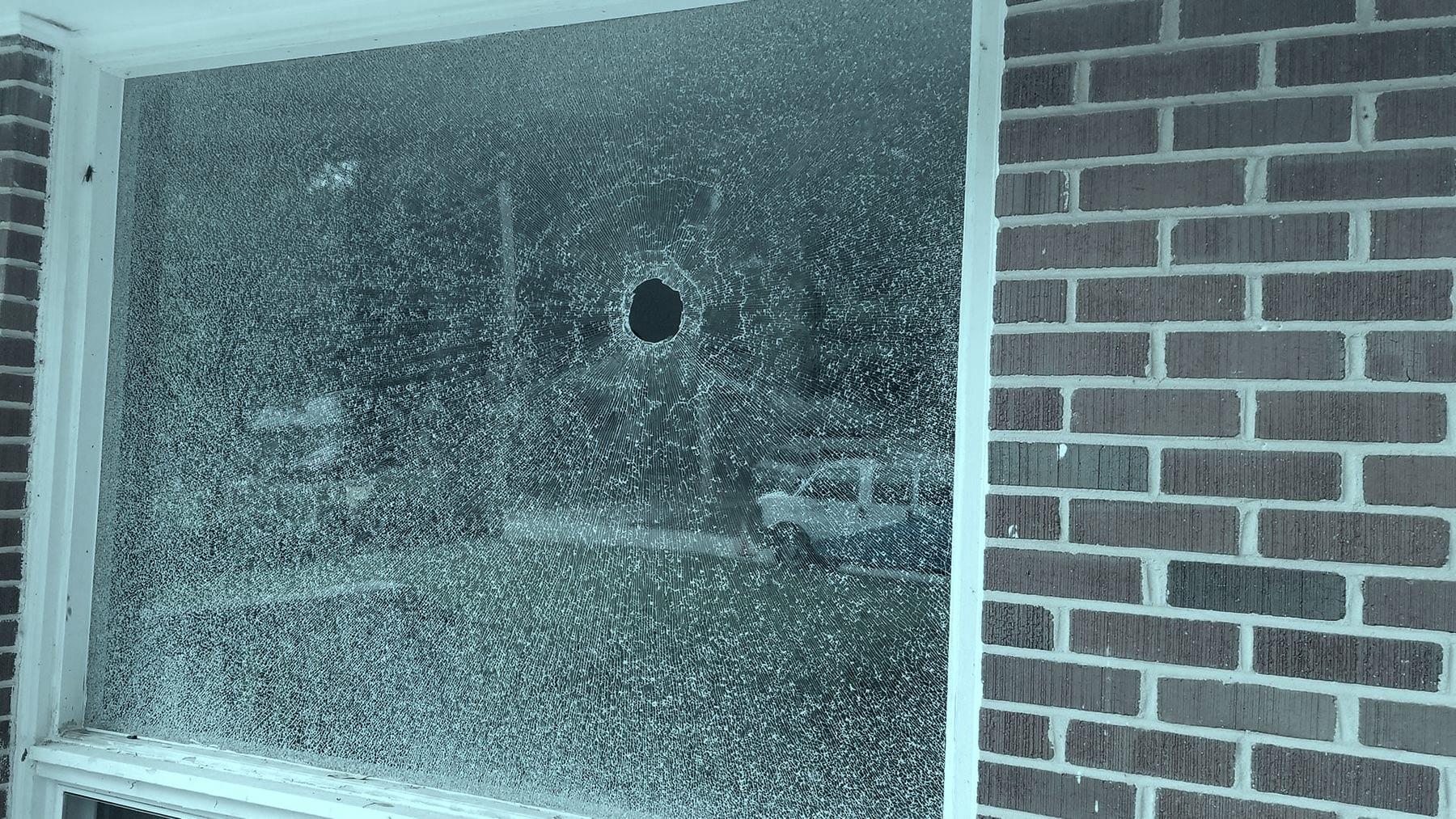 A home window shattered around a hole punched clean through the pane